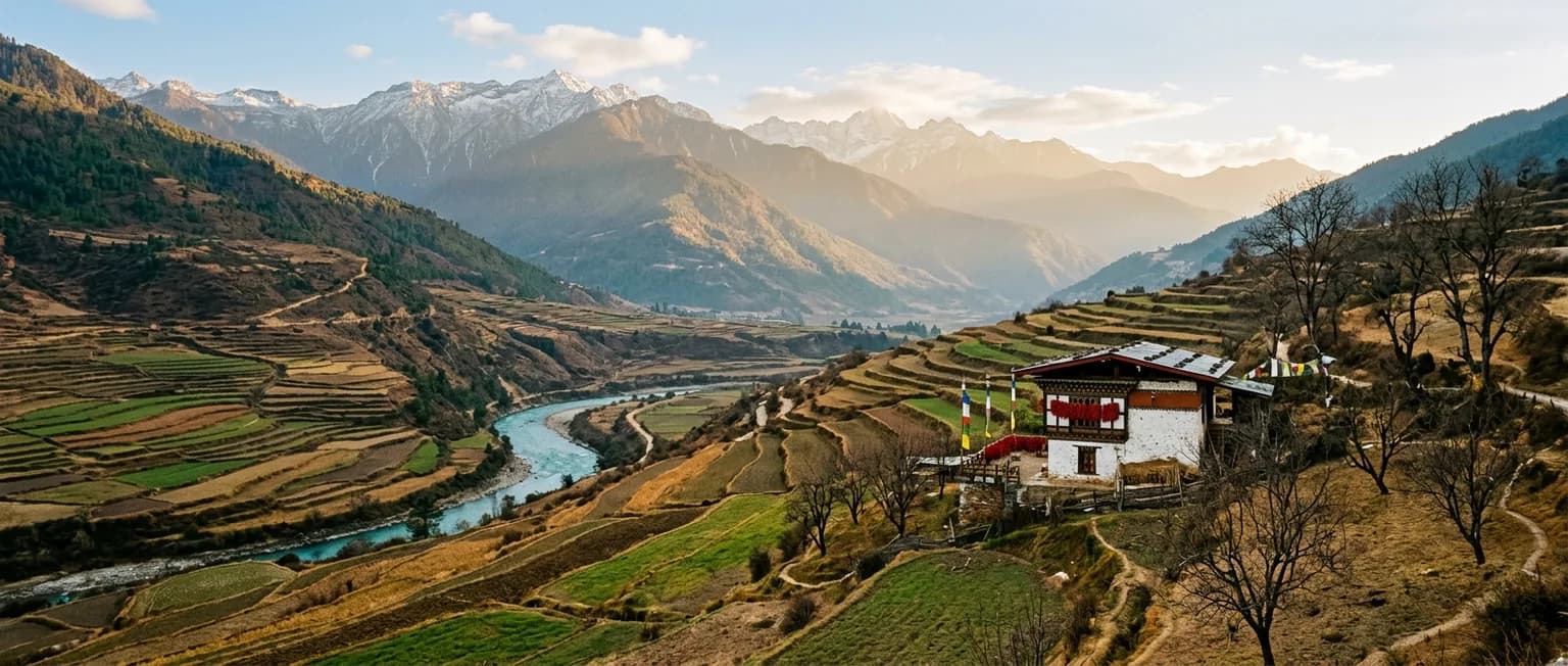 Winter sunlight over terraced fields above the Punakha river, with a whitewashed farmhouse on the slope