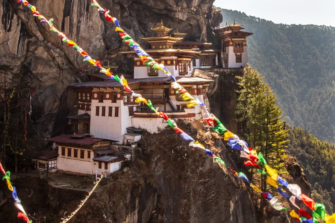 Prayer flags framing the cliffside temples of Paro Taktsang on a crisp morning walk
